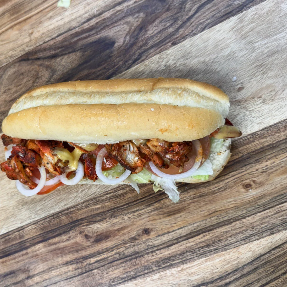 Grilled Chicken Sub with seasoned halal chicken, onions, peppers, lettuce and sauce on fresh bread